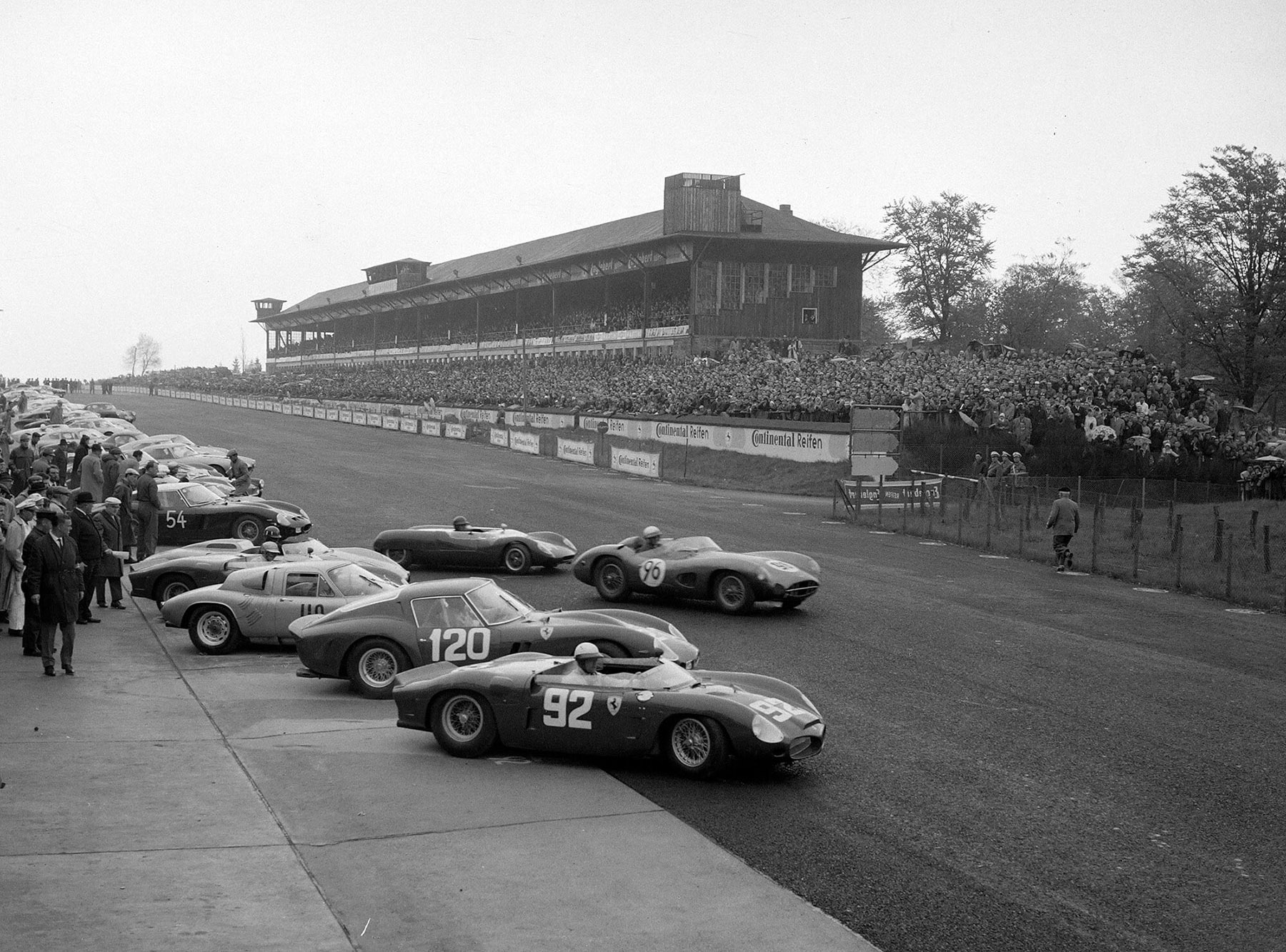 Ferrari Dino 246 SP (#92) piloted by Phil Hill and Olivier Gendebien leads chassis no. 3765 (#120) piloted by Willy Mairesse and Mike Parkes at the start of the Nürburgring 1000 kms at Nürburgring on 27 May 1962.