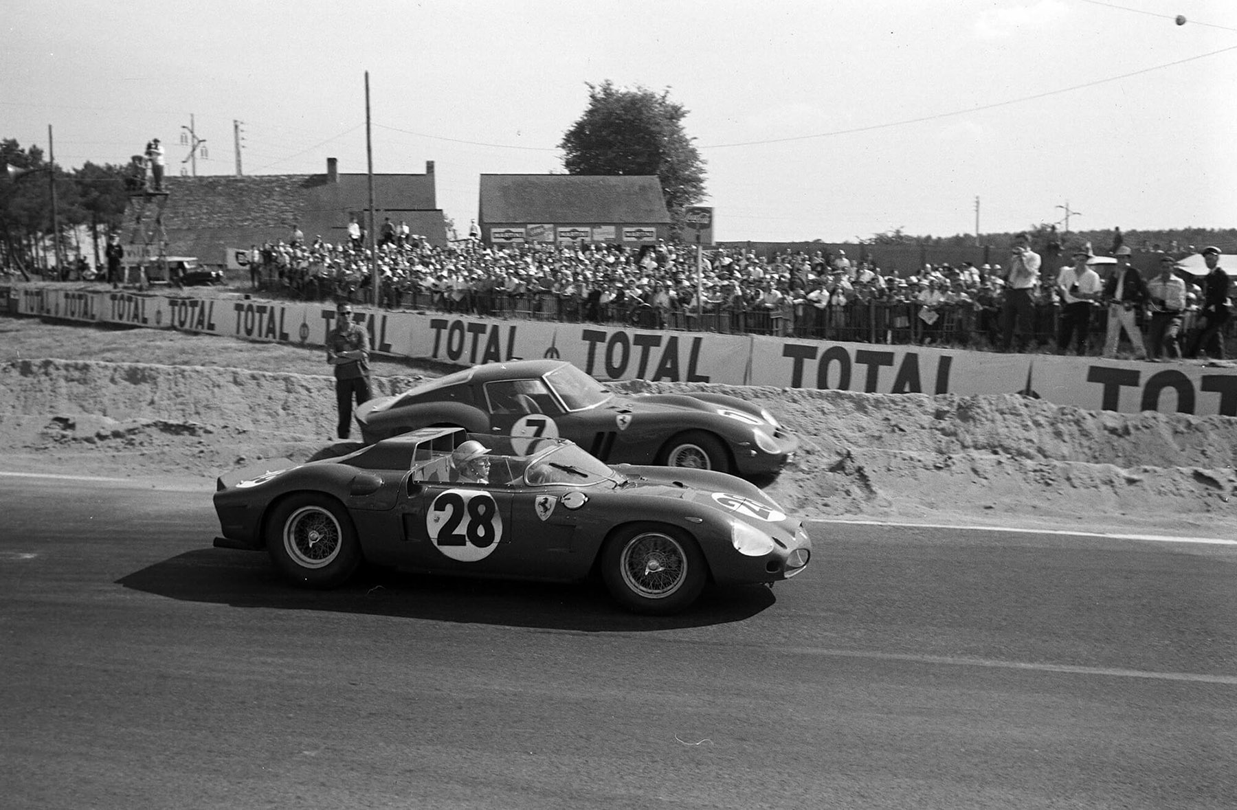 Ricardo Rodriguez and Pedro Rodriguez’s Ferrari Dino 246 SP (#28) passes Mike Parkes and Lorenzo Bandini’s Ferrari (#7) beached by the side of the track during the 24 Hours of Le Mans at Circuit de la Sarthe on 24 June 1962.
